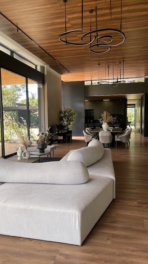 Sala amplia con sofá blanco curvo y cielorraso de madera con lámparas colgantes