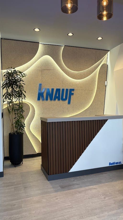 Recepción con el logo de Knauf sobre un muro con relieves iluminados