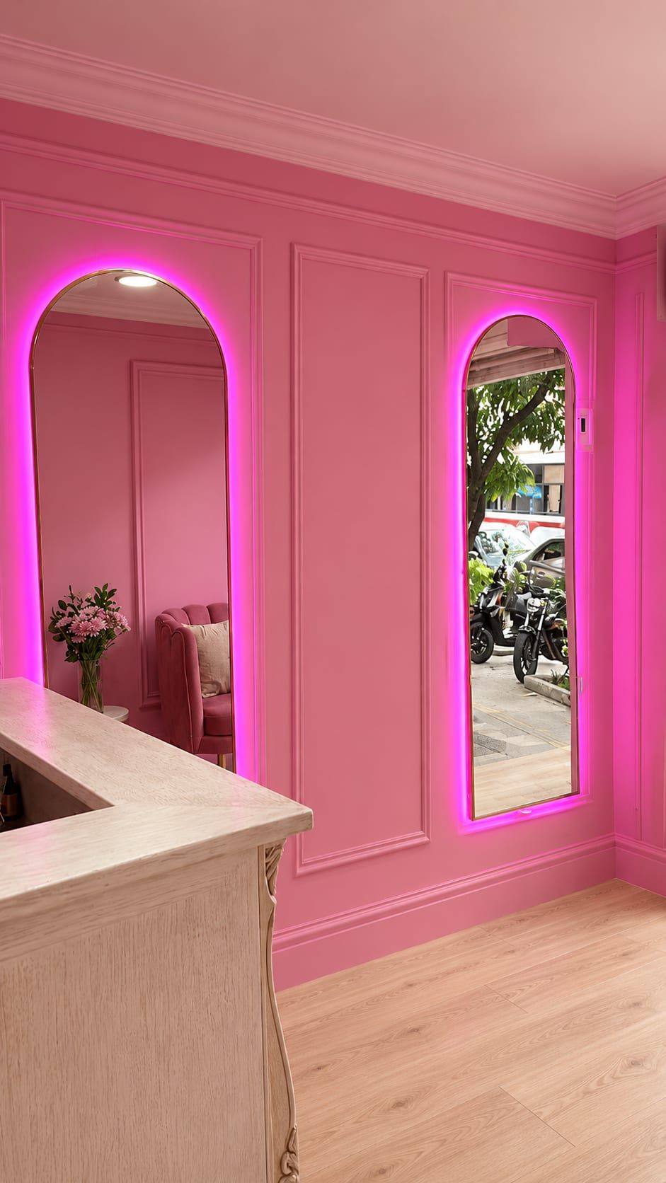 Espejos de arco con borde de neón rosa sobre un muro con molduras