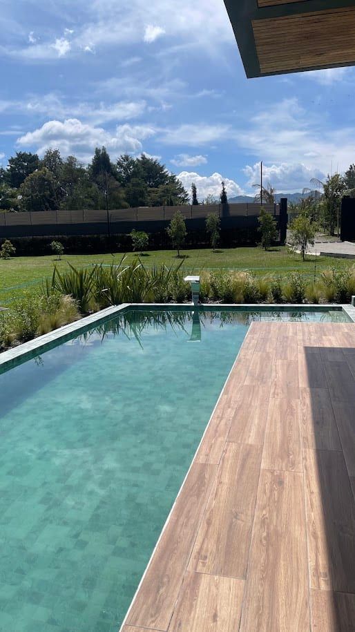 Piscina alargada con deck de madera junto a la casa