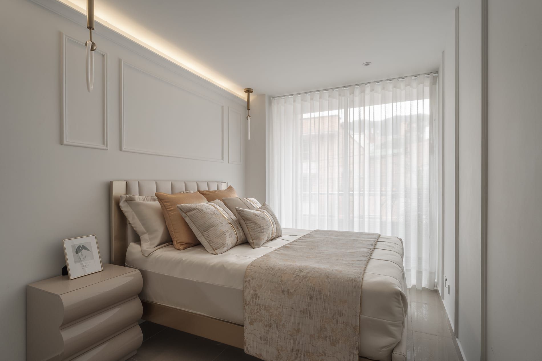 Alcoba con cama vestida en beige y muros con molduras