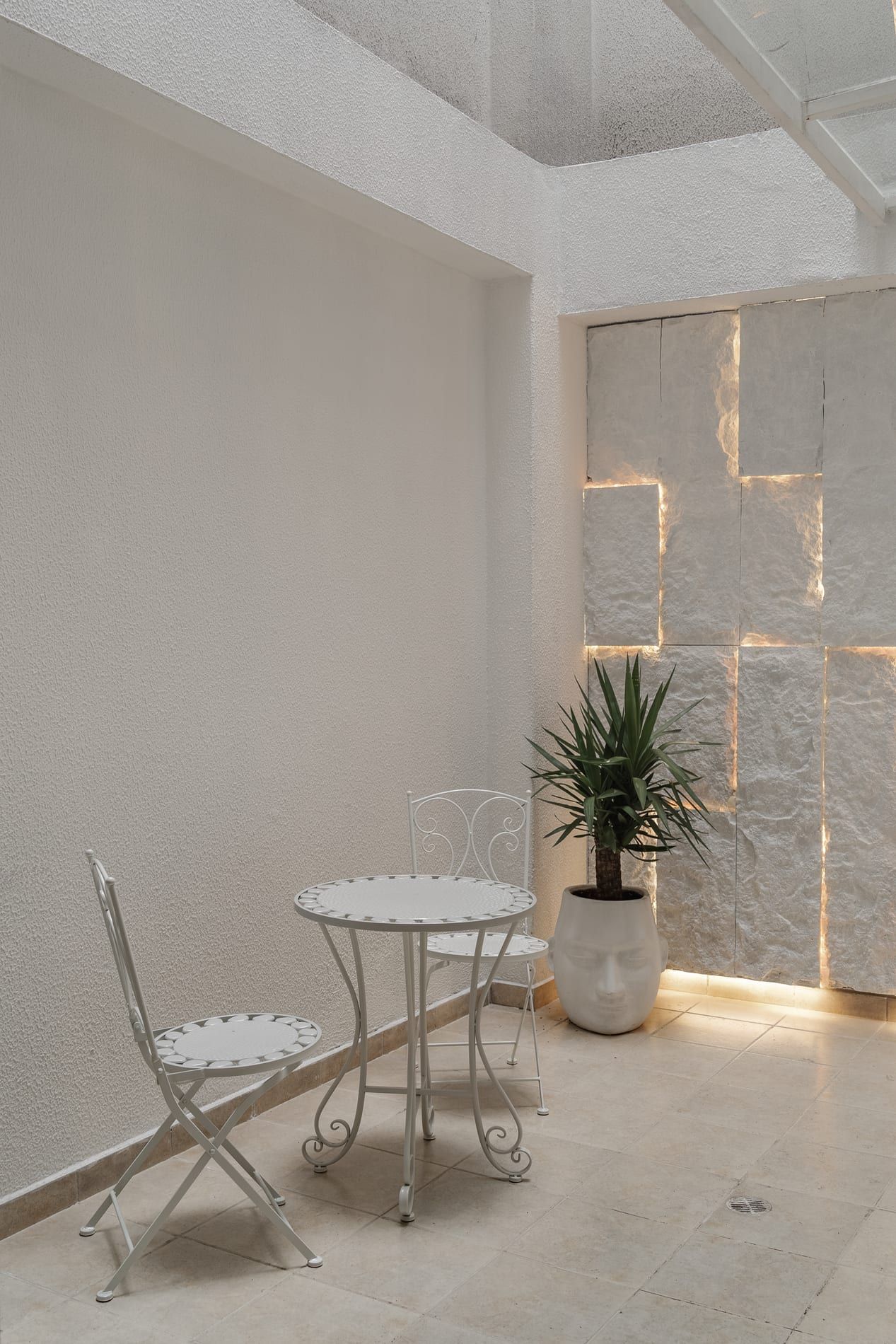 Patio con muro de piedra retroiluminado y mesa de hierro